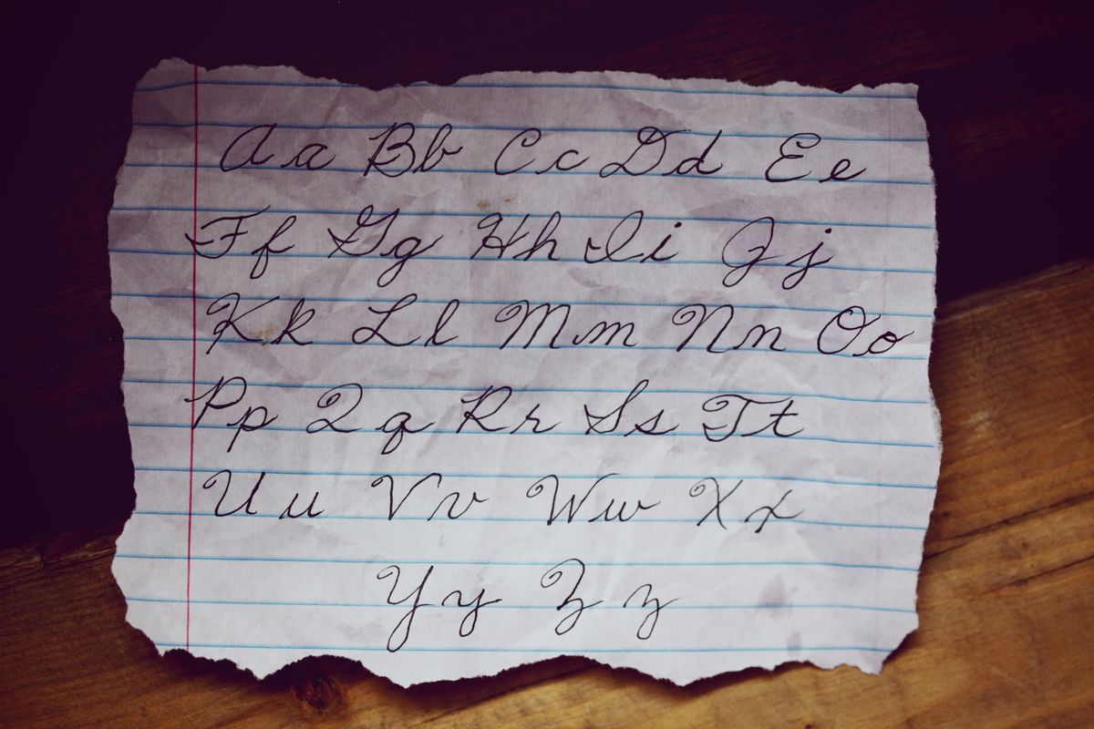 The cursive alphabet, upper and lower case, written out on lined paper